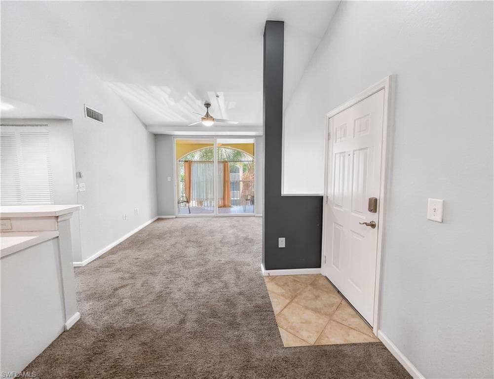 Living area featuring vaulted ceilings, a ceiling fan, plush gray carpeting, and sliding glass doors opening to an outdoor space