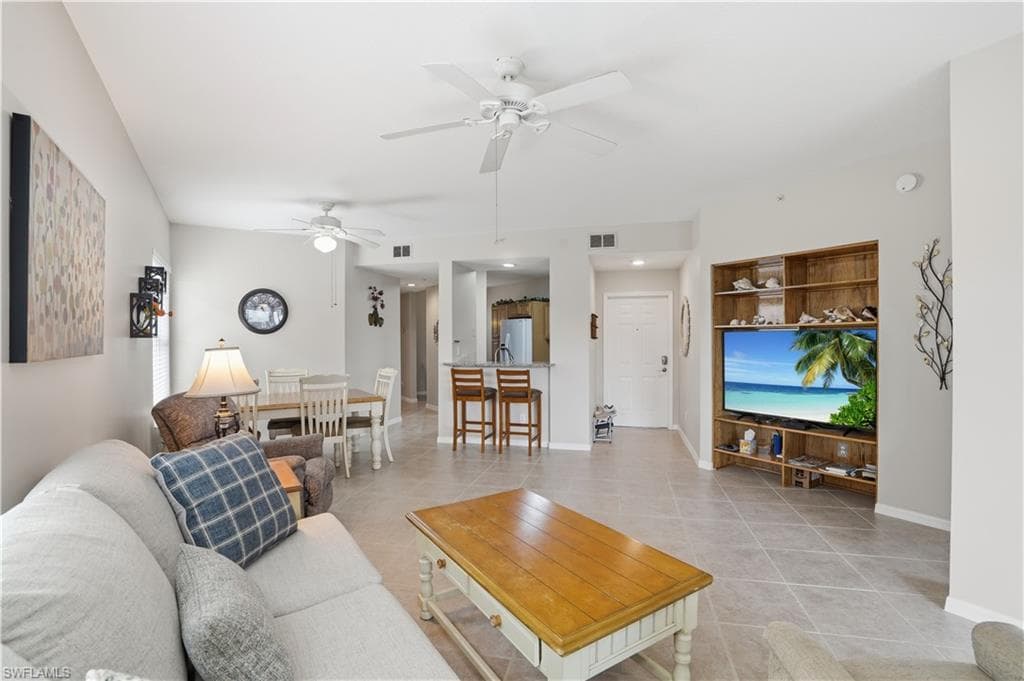 Living area featuring light tile patterned floors and a ceiling fan