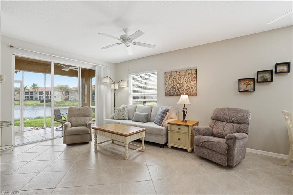 Living area featuring a ceiling fan, a water view, and light tile patterned floors