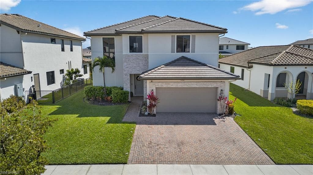 View of front of house featuring decorative driveway, stucco siding, an attached garage, and a residential view
