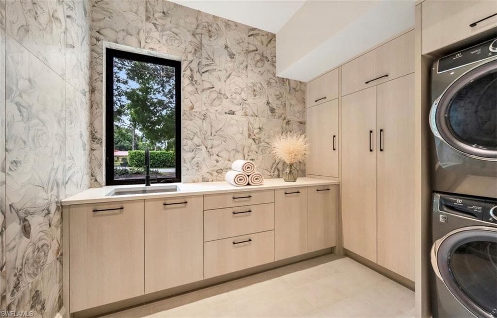 Integrated laundry appliances, extensive light-toned cabinetry, solid surface countertop, undermount sink with a matte black faucet, and organic patterned wall tiling. Only towel pyramid and floral added with AI