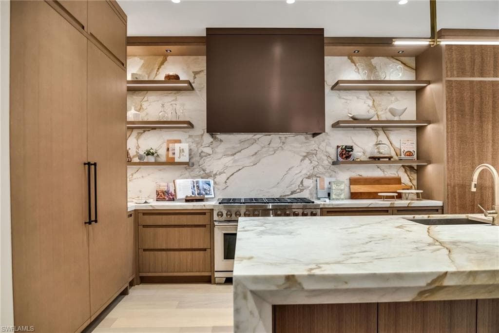 Kitchen with mitered stone island and lit floating shelves