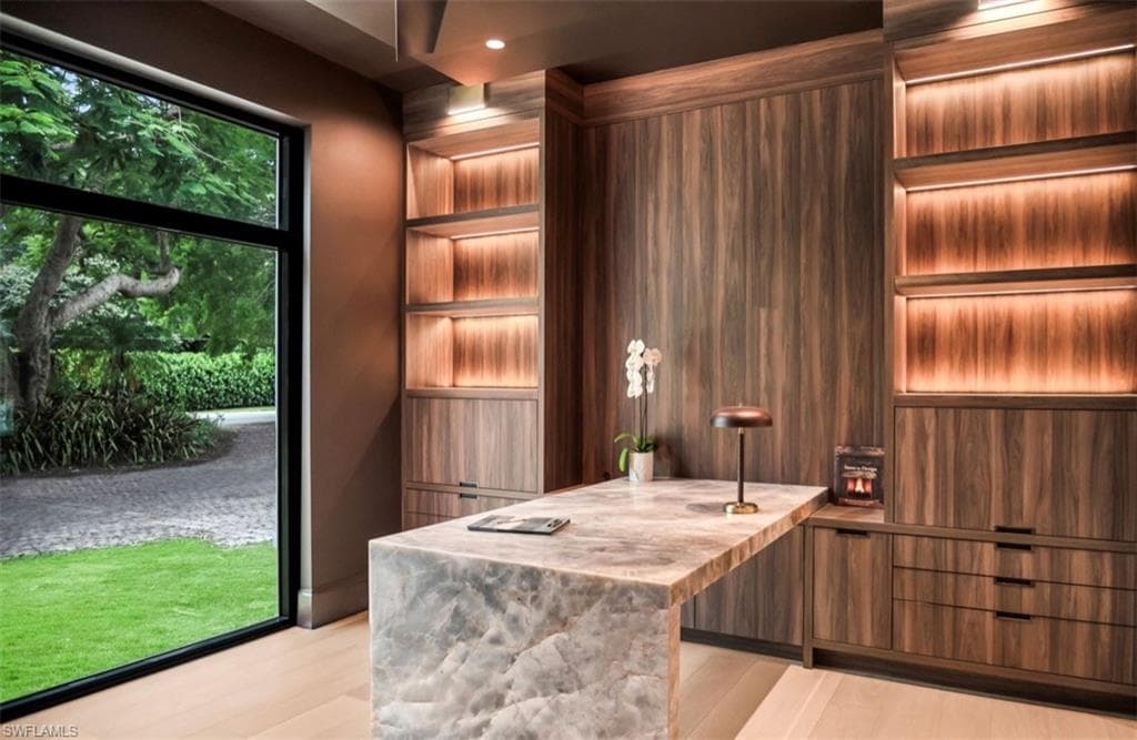 Home office with waterfall stone desk and built-in dual lit shelving
