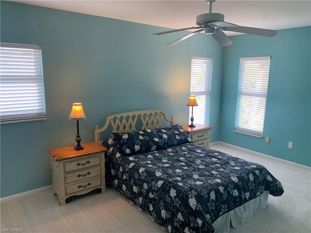 Bedroom with light colored carpet and a ceiling fan