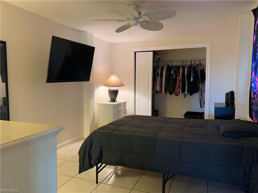 Bedroom with light tile patterned floors, a closet, and a ceiling fan