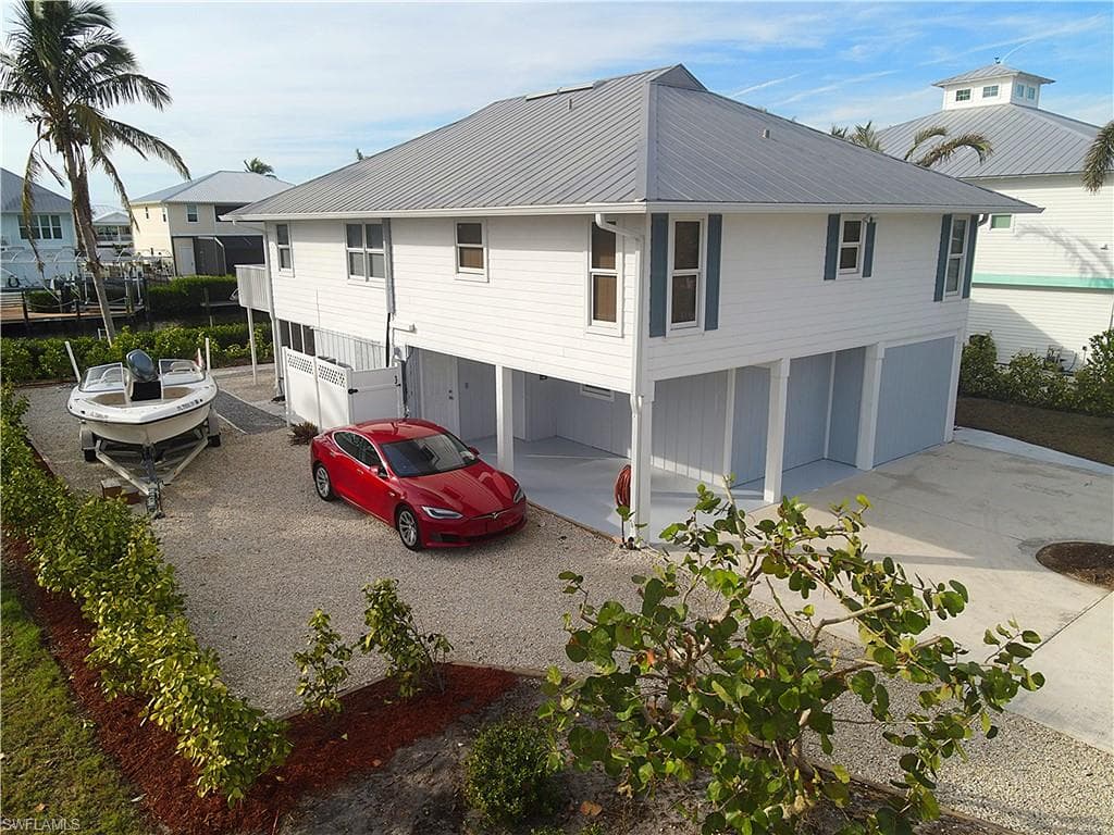 Back of property featuring a garage, a metal roof, and driveway