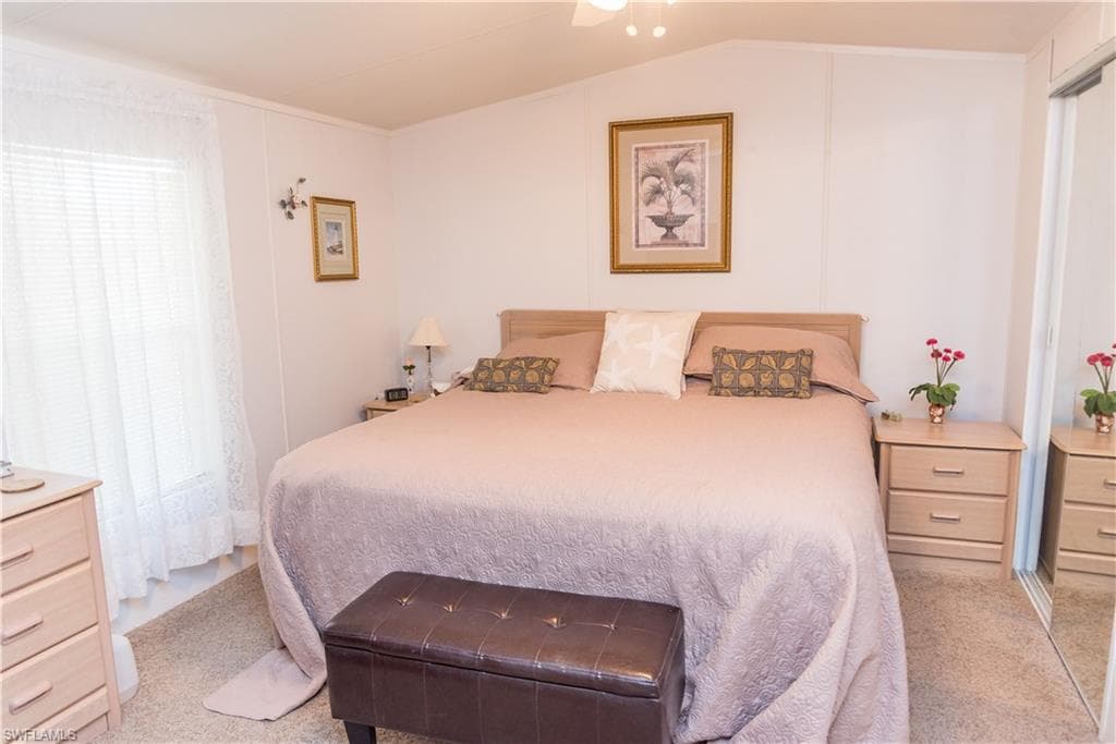 Bedroom with light colored carpet, ceiling fan, and lofted ceiling