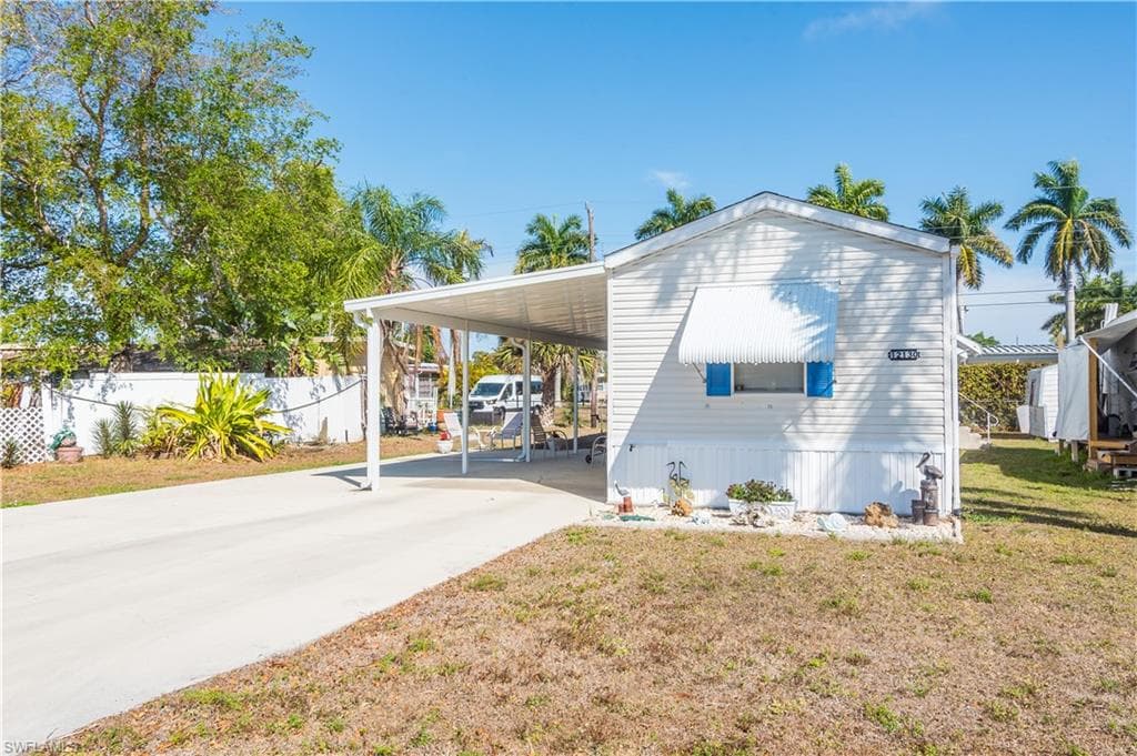 View of home's exterior featuring an attached carport, concrete driveway, and a lawn
