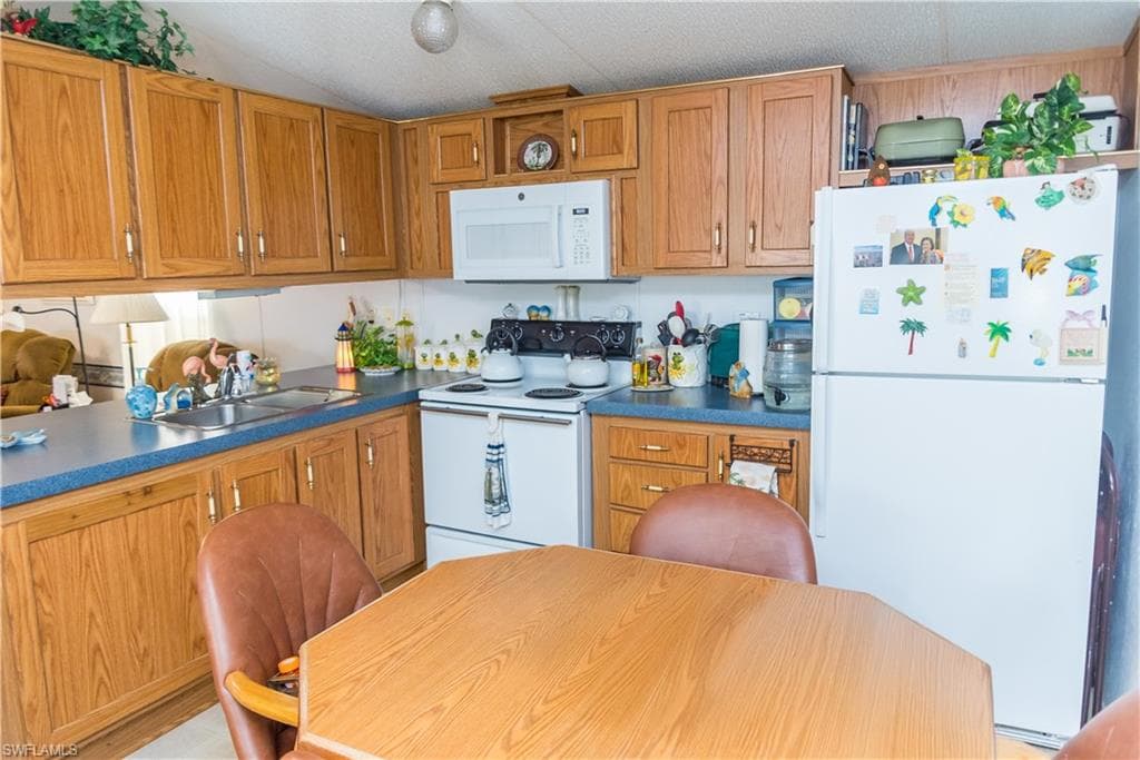 Kitchen with white appliances, wood finish cabinets, and dark countertops