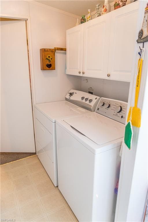 Laundry room with washer and clothes dryer, cabinet space, and light floors
