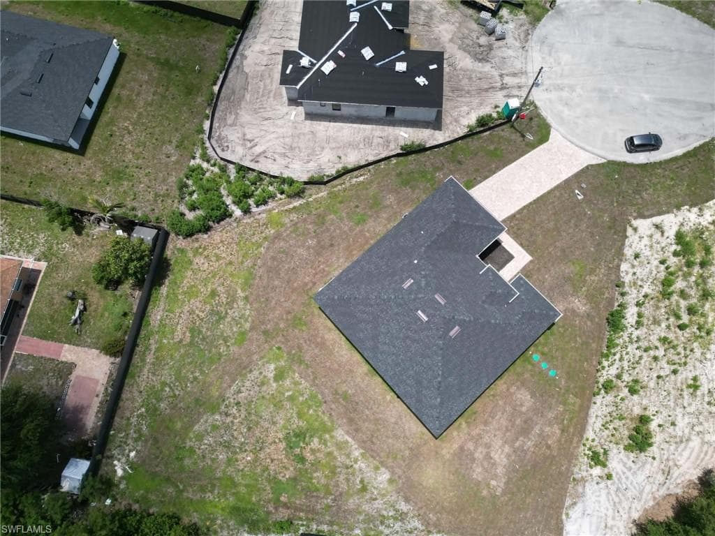 Newly constructed residence featuring a dark shingle roof and a light-colored paved driveway