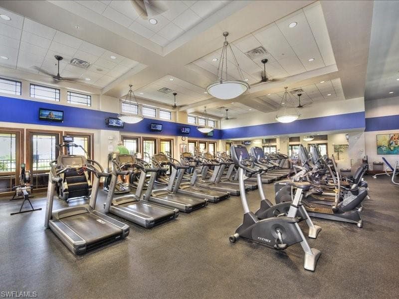 Workout area featuring ceiling fan, a towering ceiling, and coffered ceiling