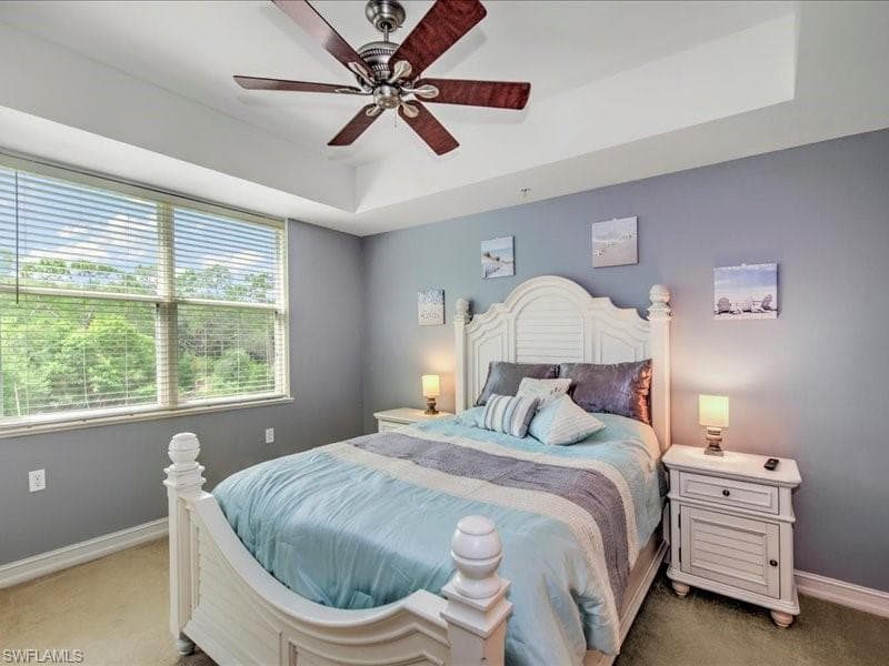 Carpeted bedroom with ceiling fan and a raised ceiling