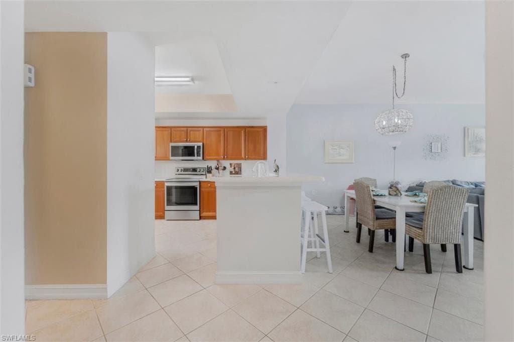 Kitchen featuring light countertops, stainless steel appliances, wood finish cabinetry, a kitchen breakfast bar, and open floor plan