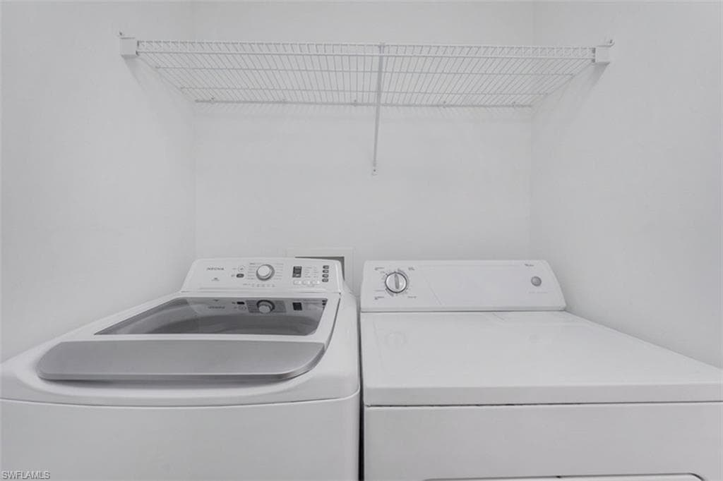Laundry area featuring a top-load washing machine, a dryer, and a wire storage shelf