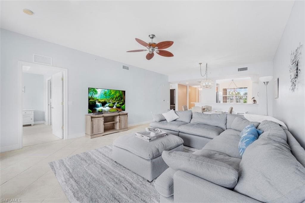 Living room with ceiling fan, hanging lights, and light tile patterned floors