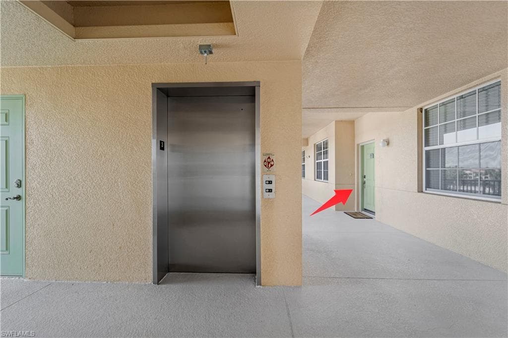 Doorway to property featuring elevator and stucco siding
