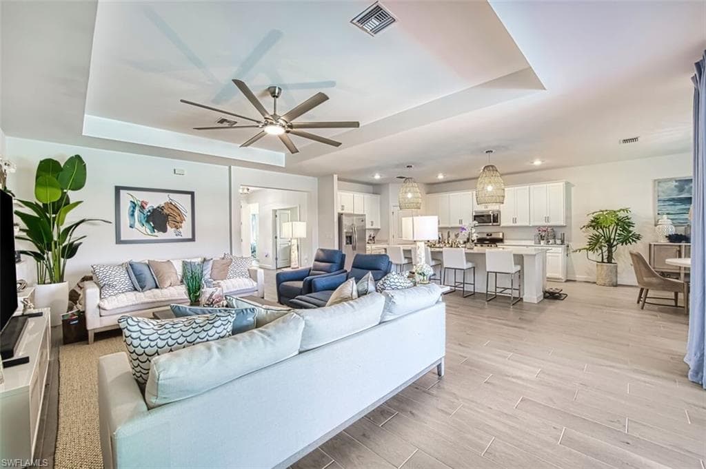 Living area featuring a raised ceiling, wood tiled floors, and a ceiling fan