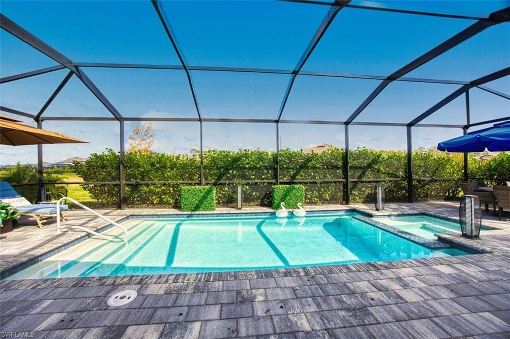 Relaxing pool / spa with a sunroom, glass enclosure, and a patio area