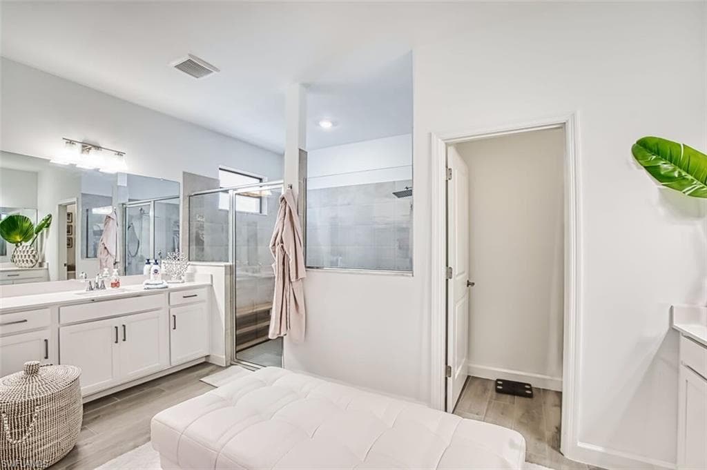 Bathroom with vanity, light wood-style flooring, and a shower stall