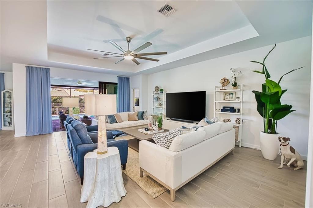 Living room featuring a tray ceiling, wood finish floors, and ceiling fan