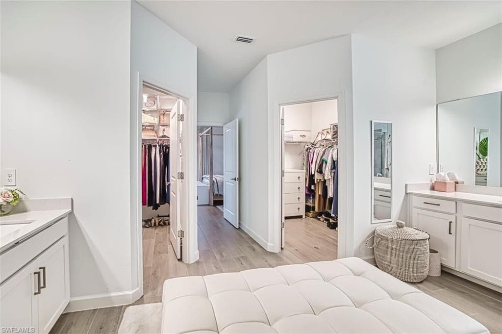 Bedroom with connected bathroom, a spacious closet, and light wood-style flooring