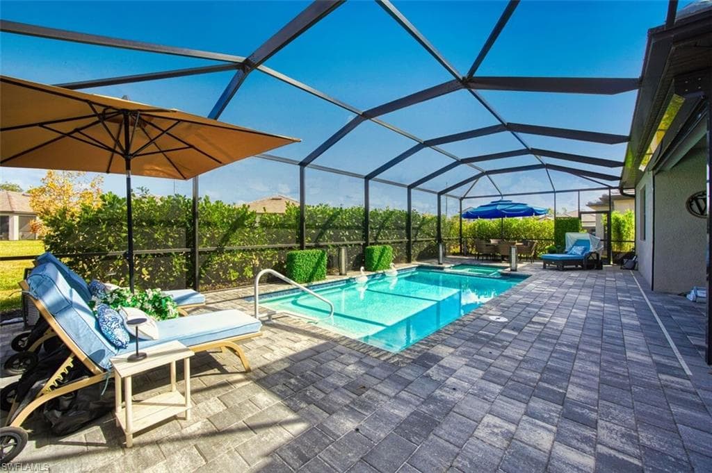 Combined pool / hot tub featuring a sunroom, glass enclosure, and a patio
