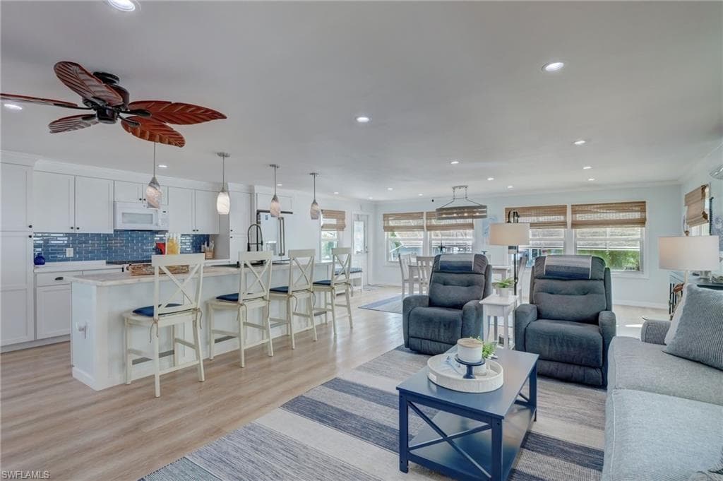Living area featuring light wood-style flooring, ceiling fan, and recessed lighting