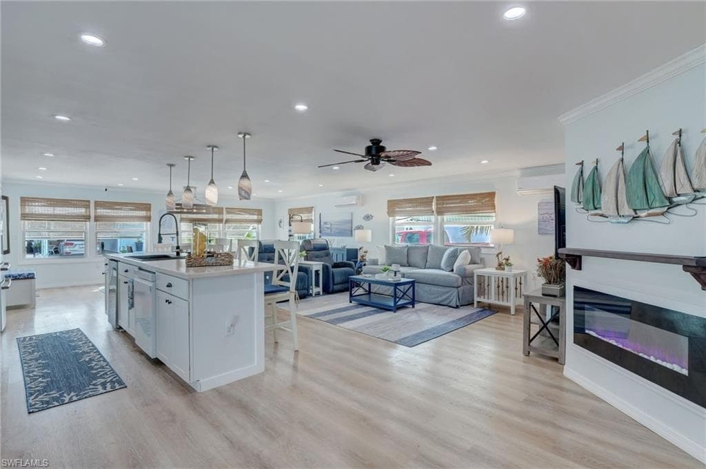 Kitchen with open floor plan, a glass covered fireplace, a breakfast bar, light wood-type flooring, and a center island with sink