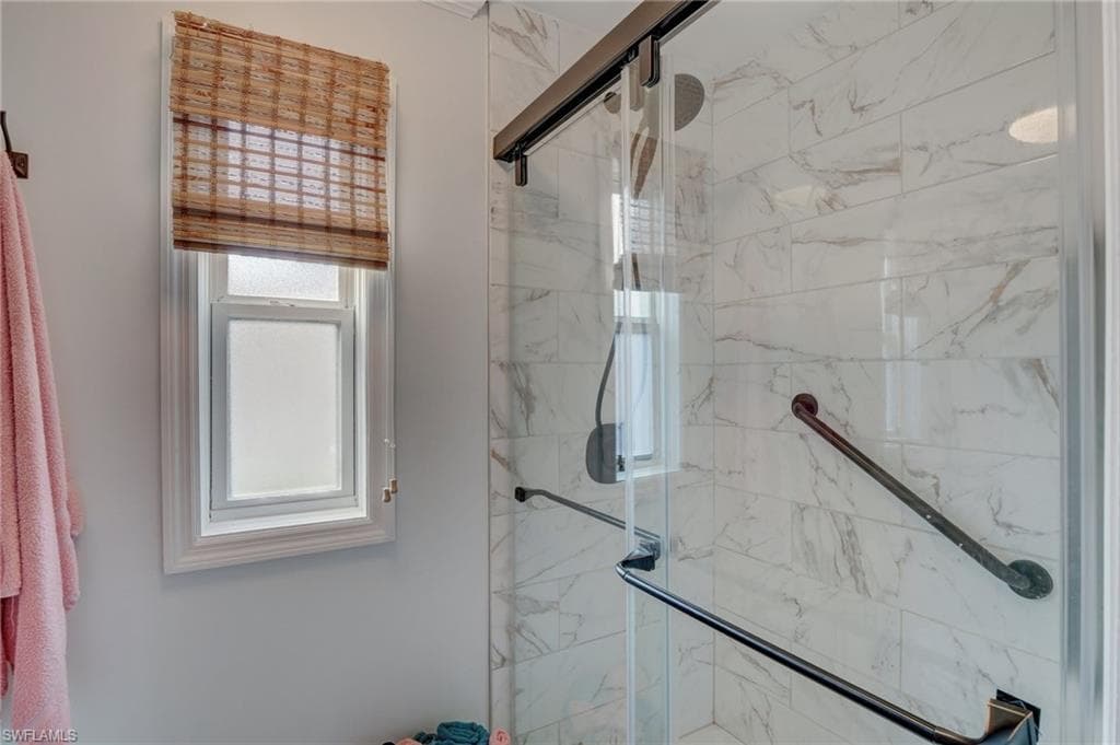 Full bath with a marble finish shower