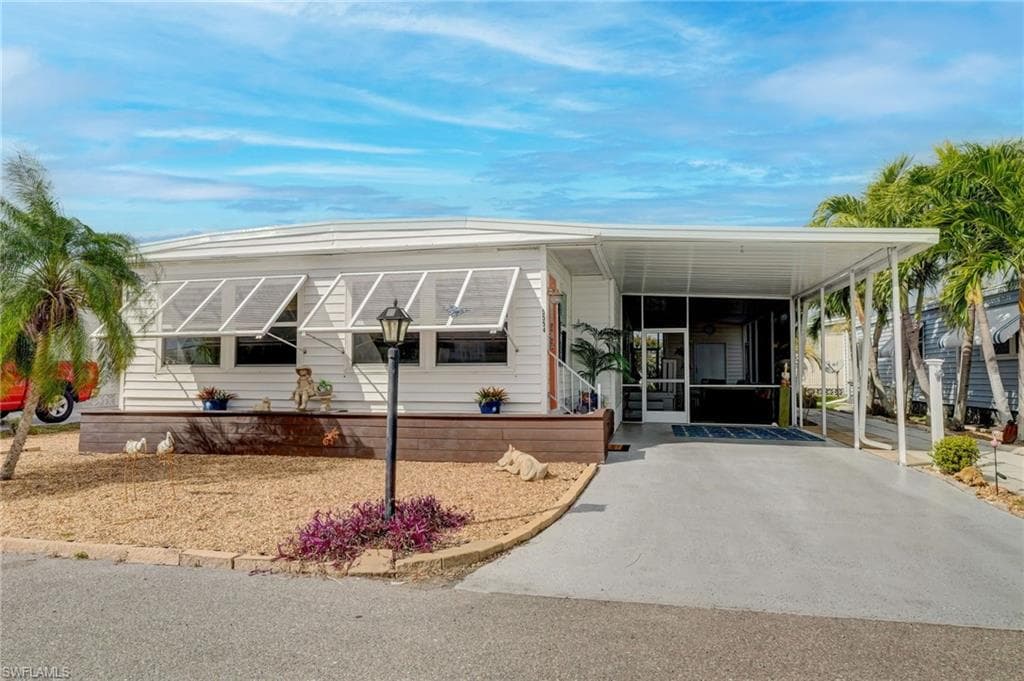 Manufactured / mobile home with an attached carport, a sunroom, and driveway