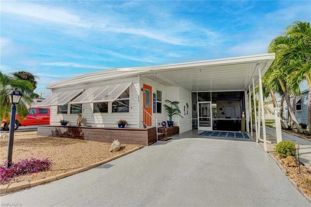 Manufactured / mobile home with an attached carport, a sunroom, and asphalt driveway