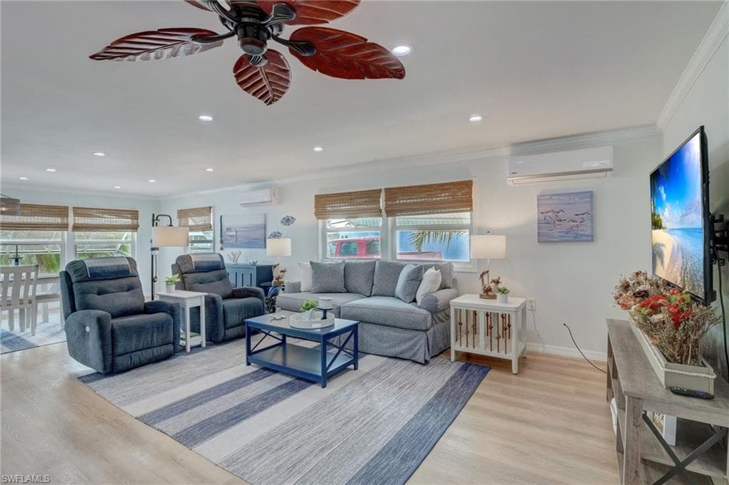 Living area with ornamental molding, a ceiling fan, light wood-style flooring, and recessed lighting