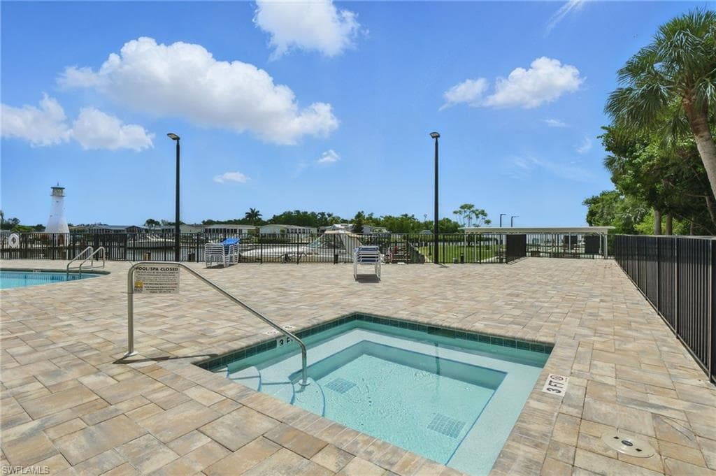Community pool with a patio and a hot tub