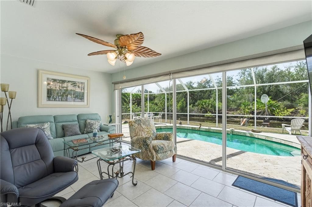 Swimming pool featuring a sunroom, ceiling fan, and view of wooded area