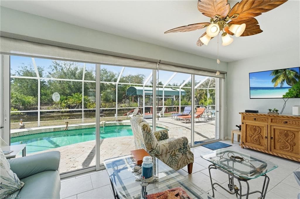 Living room with a sunroom, ceiling fan, and light tile patterned flooring