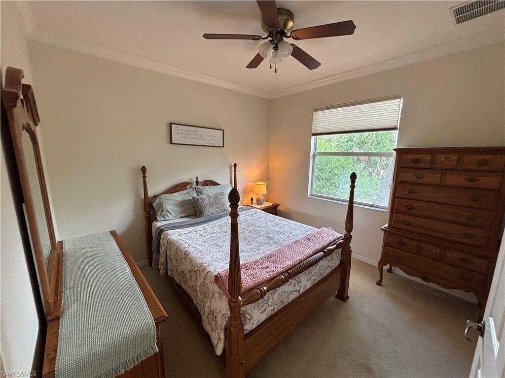 Carpeted bedroom featuring ornamental molding and ceiling fan