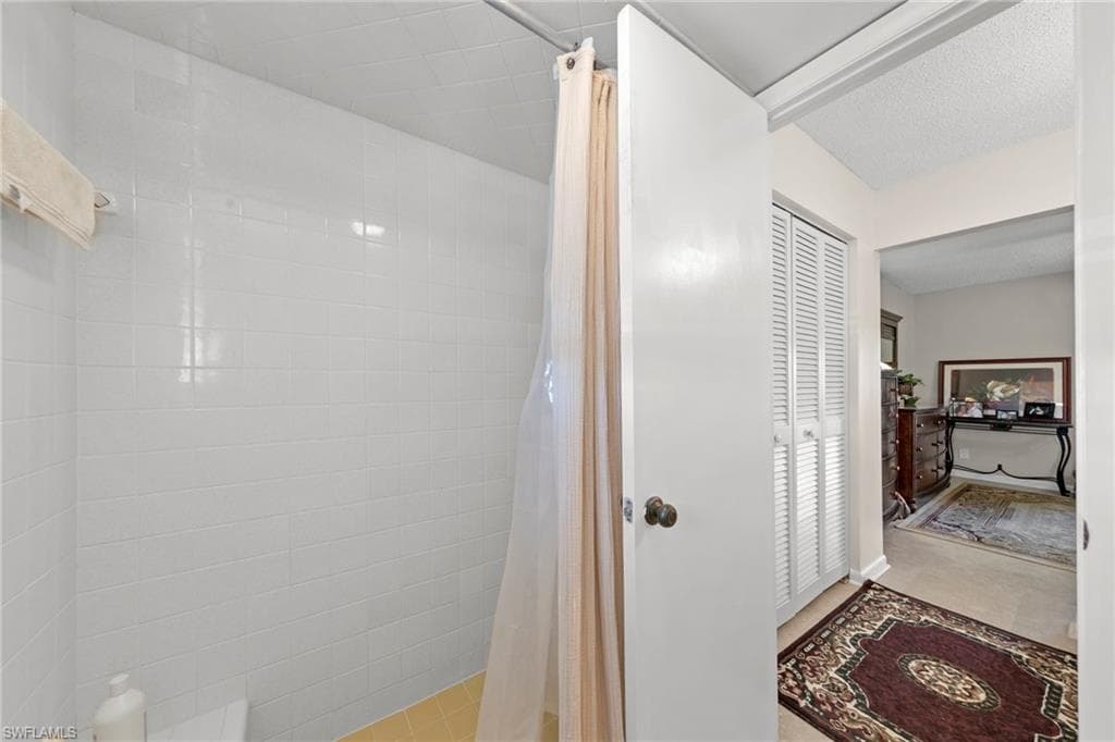 Bathroom featuring a shower stall, a closet, and a textured ceiling