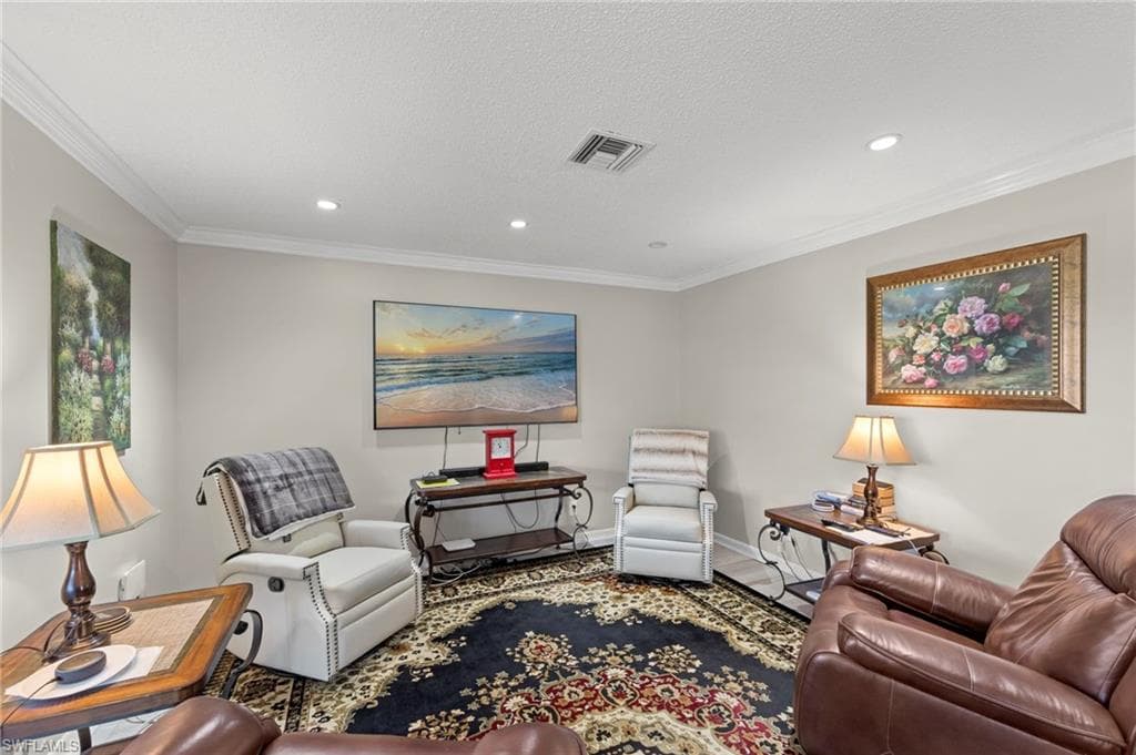 Living room with ornamental molding, recessed lighting, and a textured ceiling