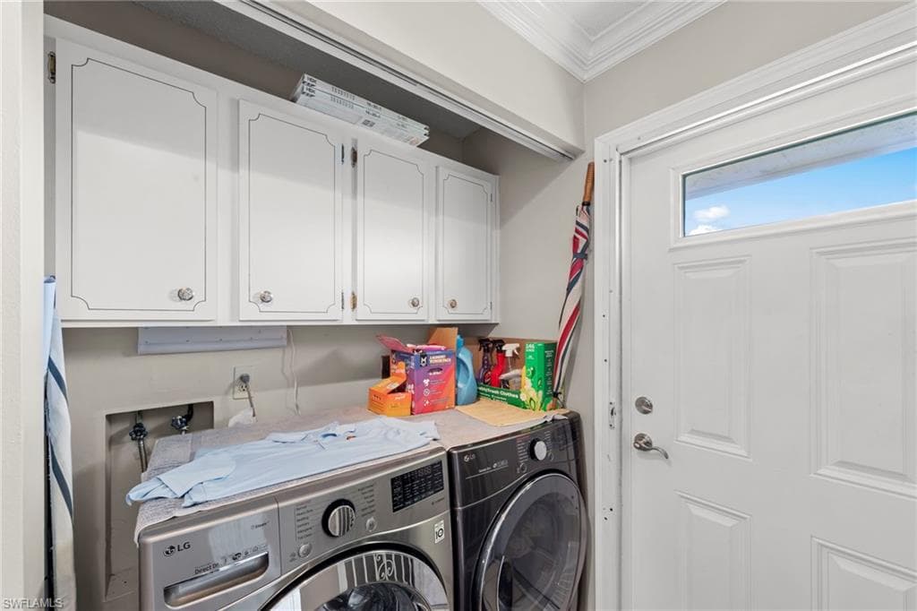 Laundry area featuring cabinet space, independent washer and dryer, and ornamental molding