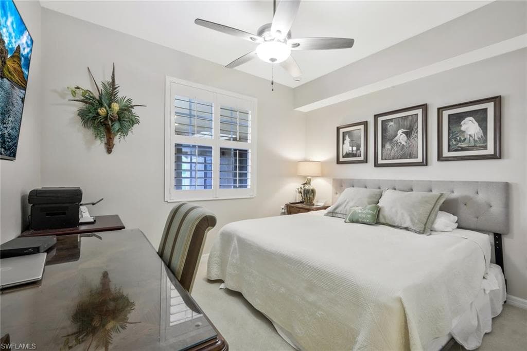 Carpeted bedroom with a ceiling fan and an office area