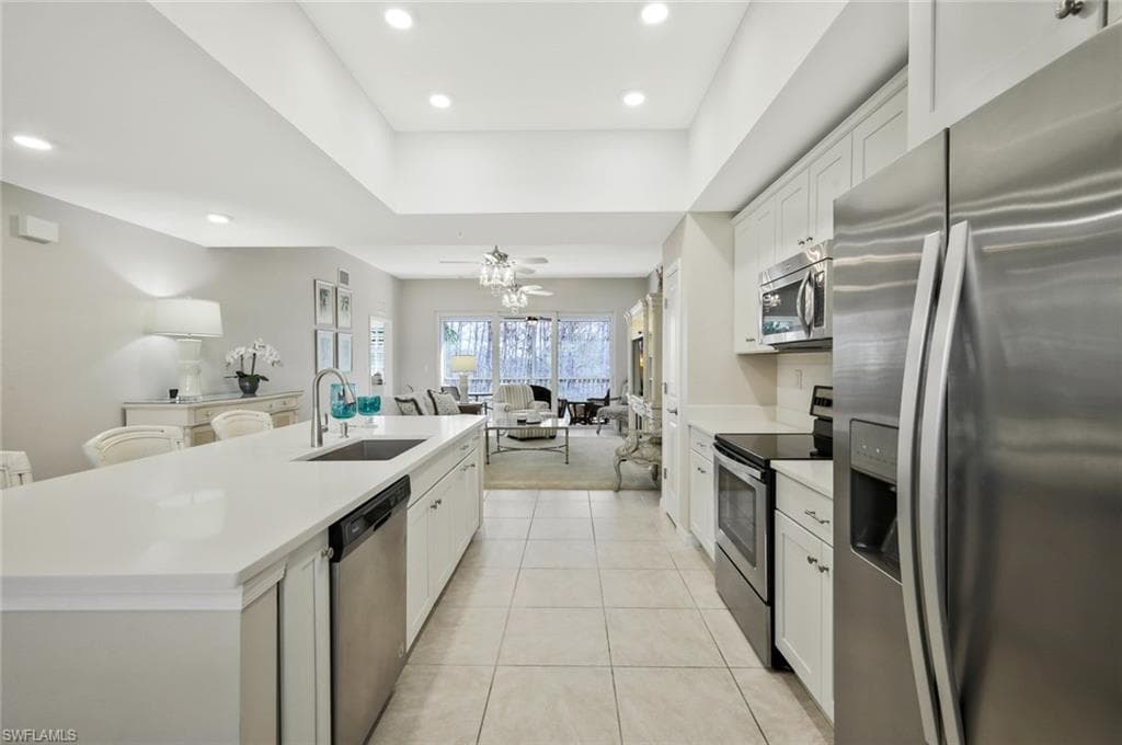 Kitchen featuring stainless steel appliances, open floor plan, a kitchen island with sink, white cabinets, and recessed lighting