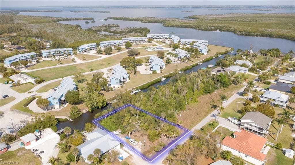 Aerial perspective of suburban area featuring property parcel outlined and a nearby body of water