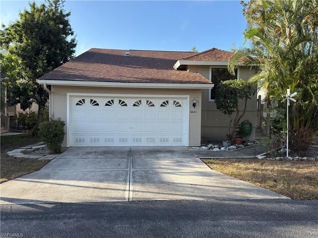 Ranch-style house with roof with shingles, concrete driveway, and an attached garage