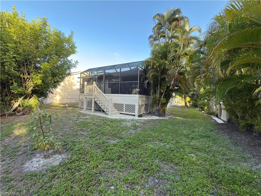 View of grassy yard with a lanai, a sunroom, and a deck
