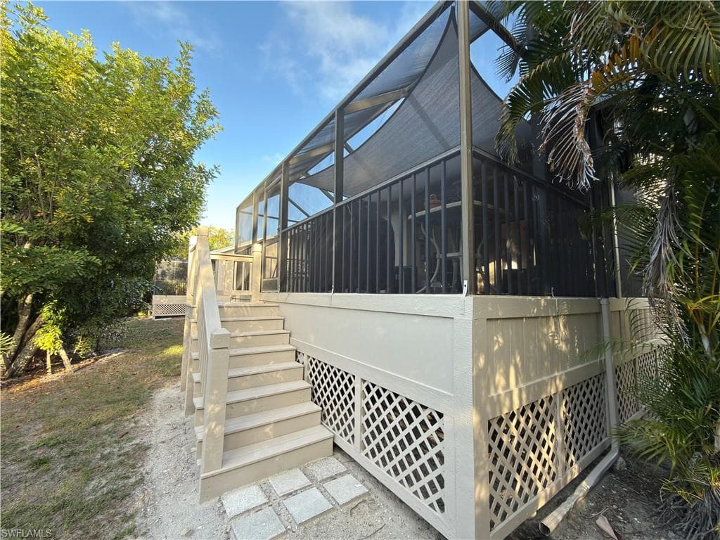 View of side of home featuring a sunroom, a wooden deck, and a lanai