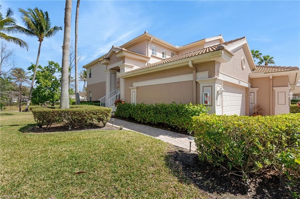 Mediterranean / spanish-style home featuring a garage, stucco siding, a tiled roof, and a front lawn