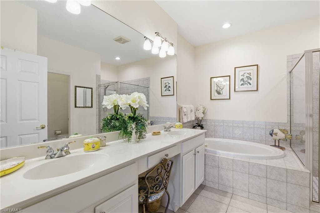 Bathroom with double vanity, a garden tub, a stall shower, and light tile patterned floors