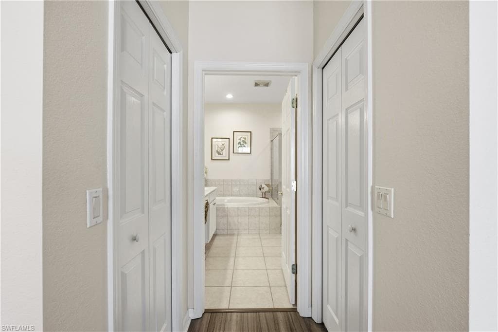 Corridor featuring a textured wall, dark tile patterned floors, and recessed lighting