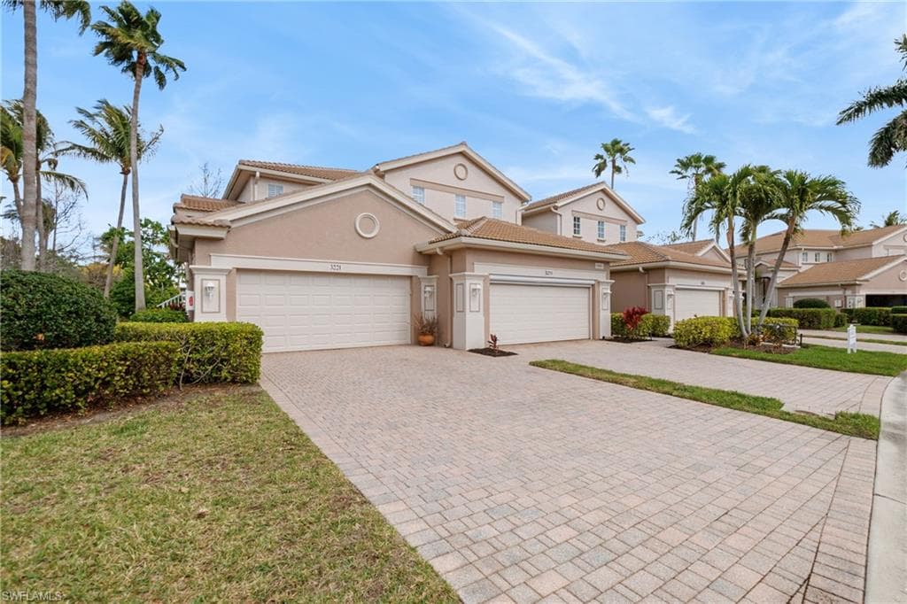 View of front of house featuring stucco siding, decorative driveway, a tile roof, and an attached garage